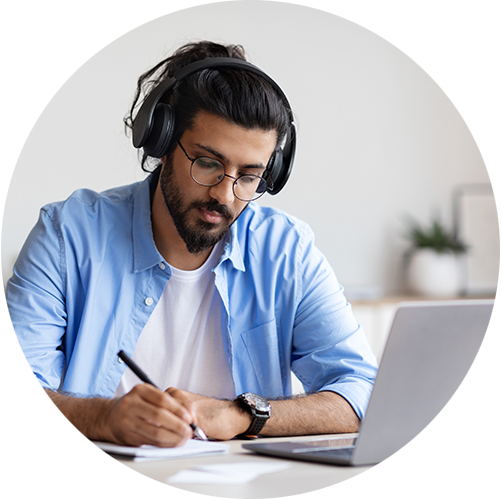 A person wearing headphones studying on a laptop