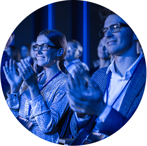 People in a conference room style room, looking forward clapping.